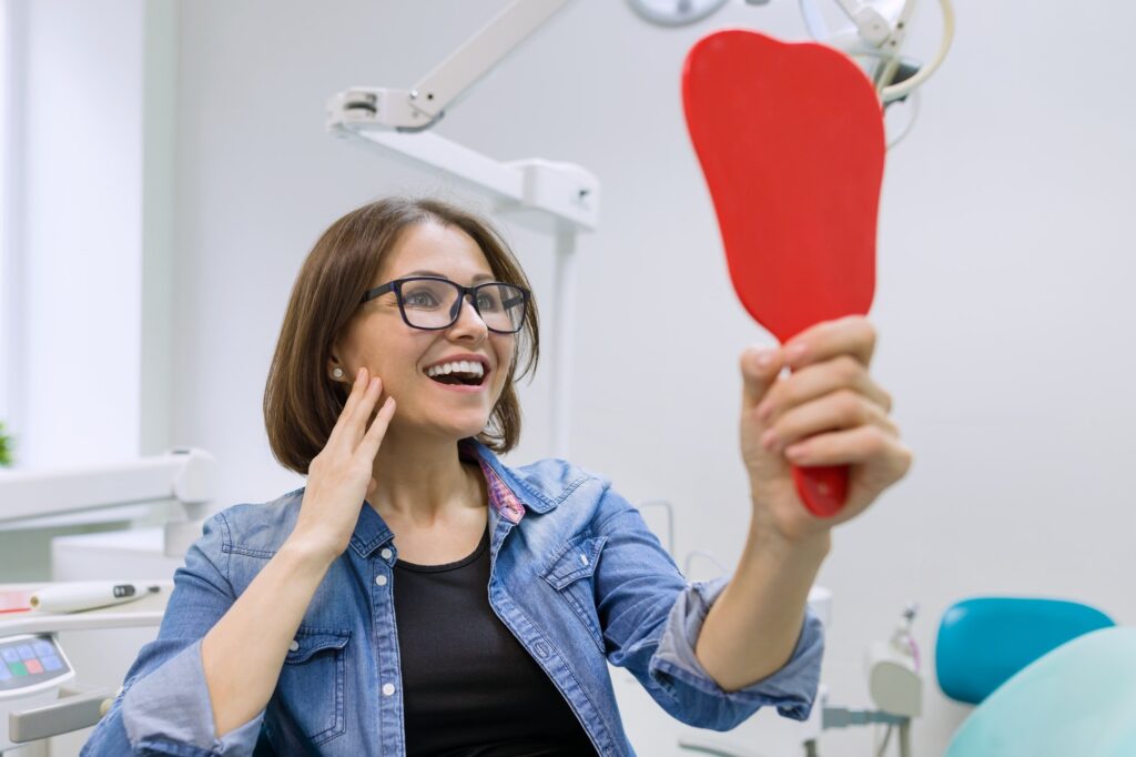 Patient looking in the mirror, impressed with her dental treatment results at Wichita Family Dental.
