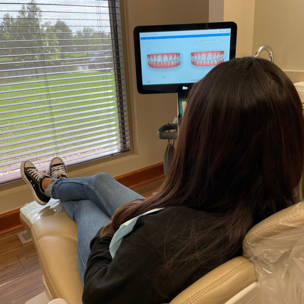 Female patient examining model of teeth on digital display in exam room at Wichita Family Dental, engaging in her treatment plan.