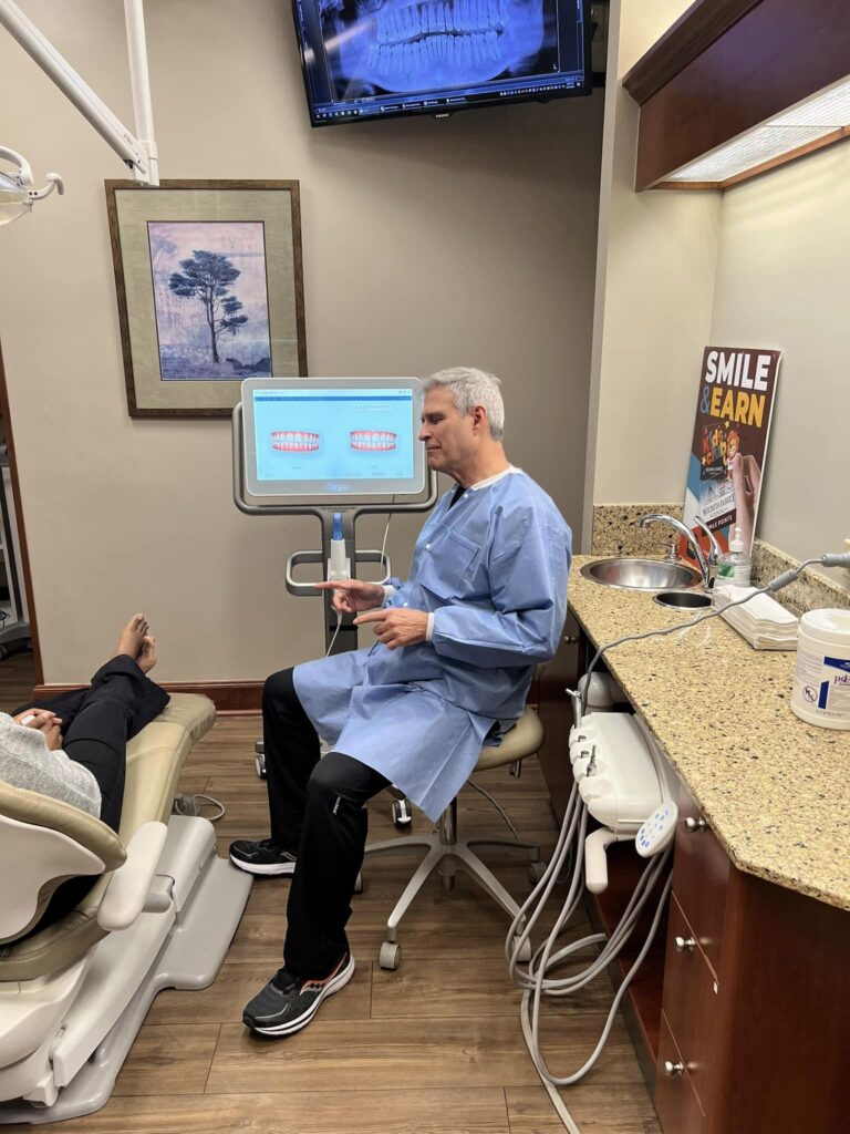 Dr. Pierson at Wichita Family Dental discussing treatment options with a patient near a digital monitor, ensuring informed decisions.