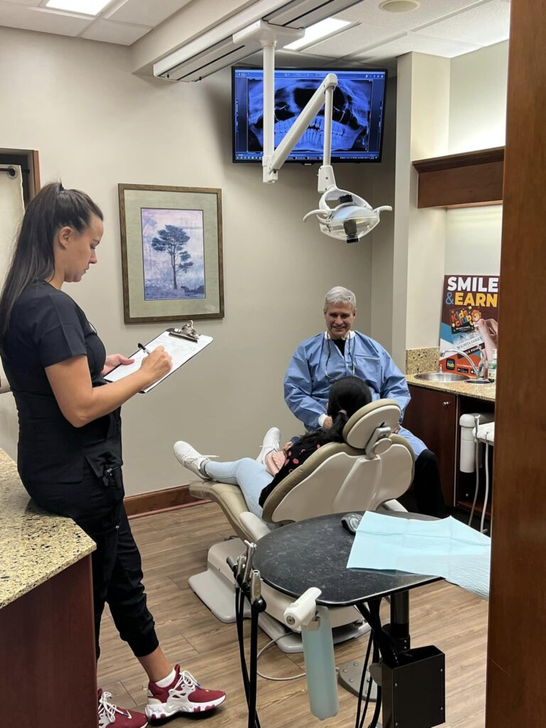 Dr. Pierson discussing dental information with a hygienist taking notes at Wichita Family Dental, highlighting teamwork.