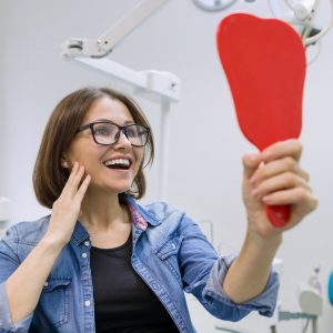 Patient looking in the mirror, impressed with her dental treatment results at Wichita Family Dental.
